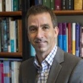 a smiling picture of Matthias Henze, with bookshelf in the background